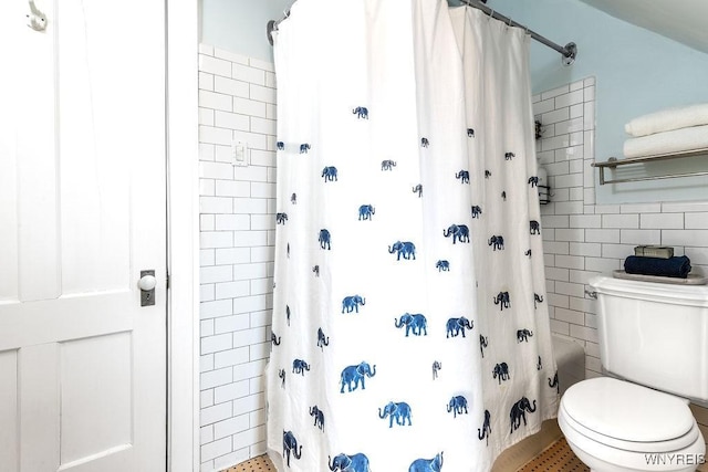 bathroom featuring toilet and tile walls