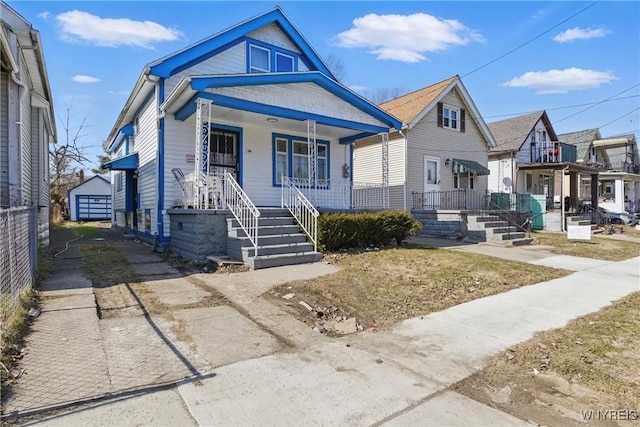 view of front facade with fence, a porch, an outdoor structure, concrete driveway, and a detached garage