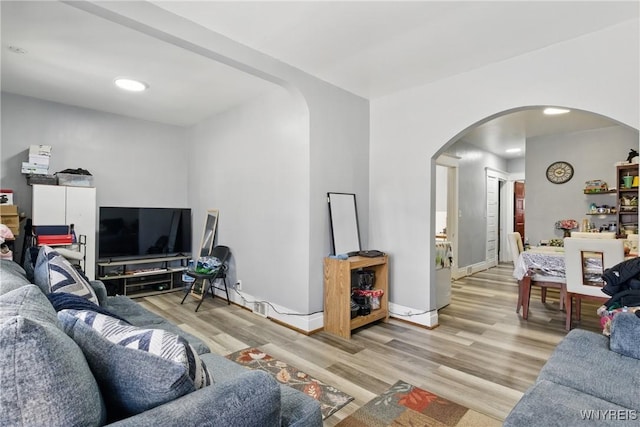 living area with wood finished floors, arched walkways, and baseboards