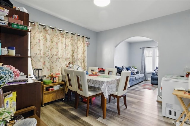 dining room featuring wood finished floors and arched walkways