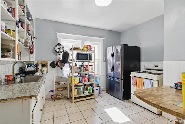 kitchen featuring light countertops, light tile patterned floors, appliances with stainless steel finishes, white cabinets, and a sink