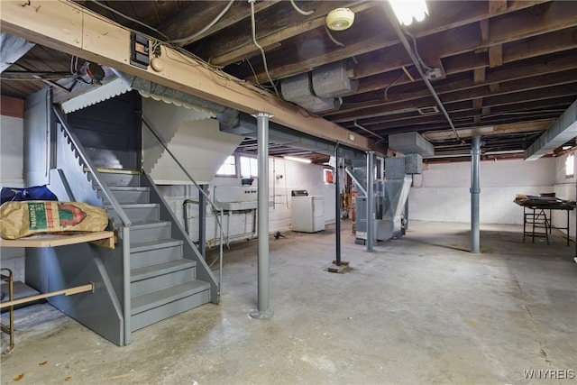 below grade area featuring stairs, heating unit, and independent washer and dryer