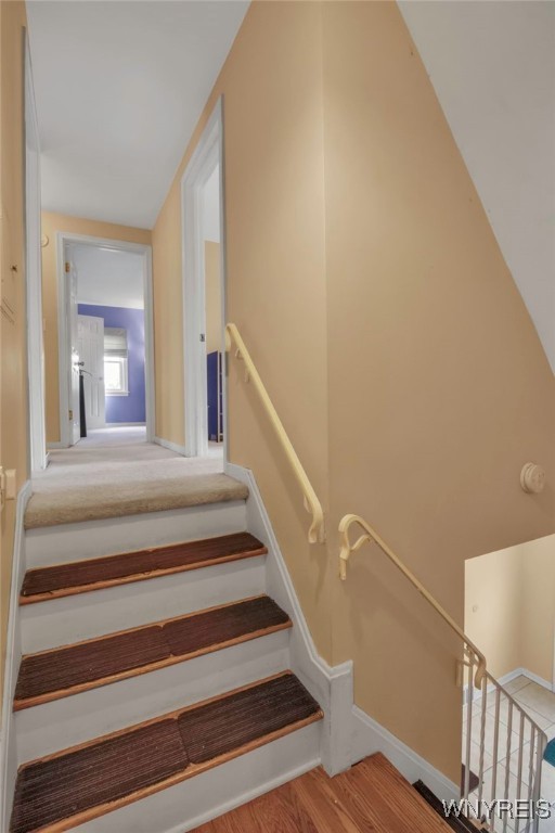 stairs with wood finished floors and baseboards