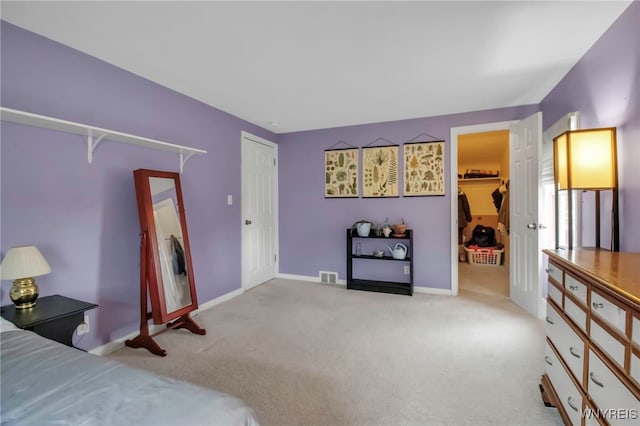 bedroom with visible vents, a walk in closet, a closet, carpet floors, and baseboards