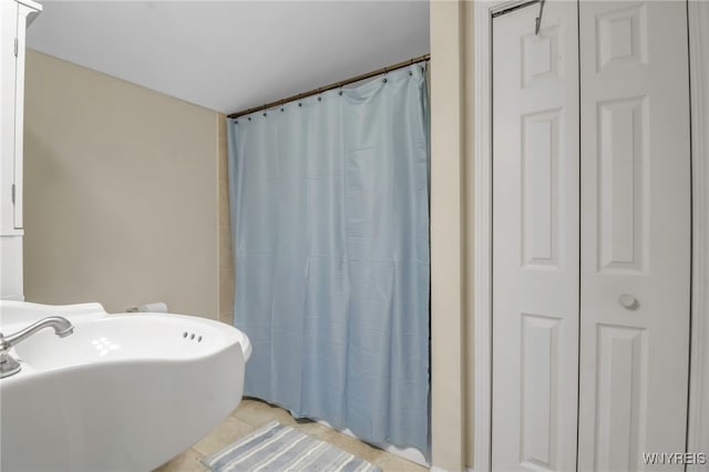 full bath with tile patterned flooring, a shower with shower curtain, and a sink