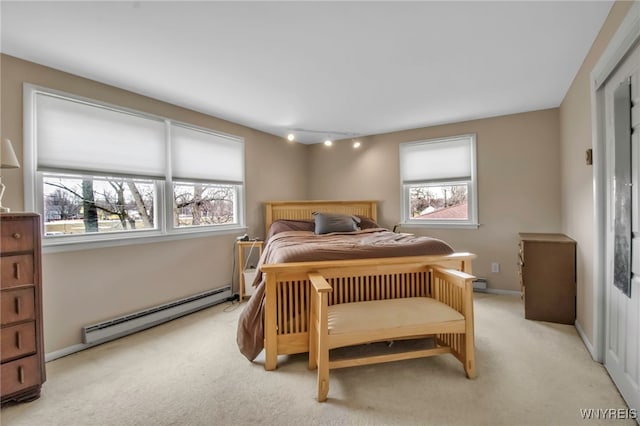 bedroom featuring light colored carpet, a baseboard heating unit, and baseboards