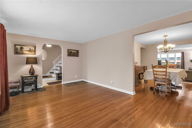 living room featuring stairs, wood finished floors, baseboards, and a chandelier