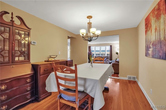 dining space with a notable chandelier, visible vents, baseboards, and light wood-style floors