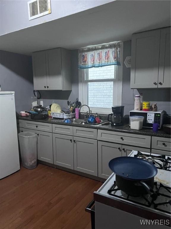 kitchen featuring dark wood finished floors, dark countertops, visible vents, and freestanding refrigerator