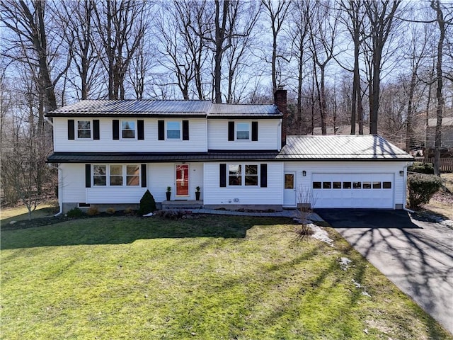 traditional-style home featuring a front lawn, aphalt driveway, a chimney, metal roof, and a garage