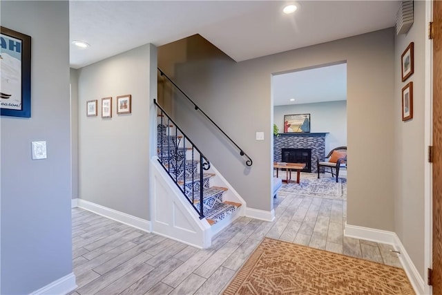 stairway with a tiled fireplace, baseboards, and wood tiled floor