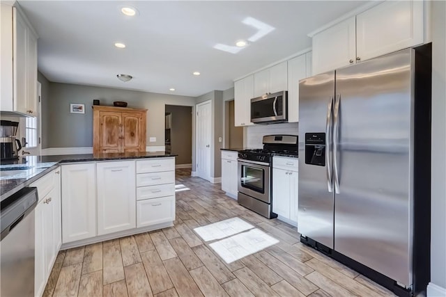 kitchen featuring wood tiled floor, a peninsula, recessed lighting, stainless steel appliances, and white cabinetry