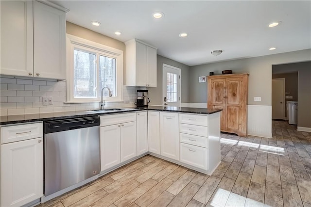 kitchen featuring a sink, light wood-type flooring, dishwasher, and a peninsula