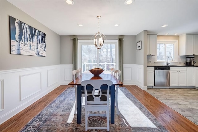 dining area with recessed lighting, light wood-style flooring, and a wainscoted wall