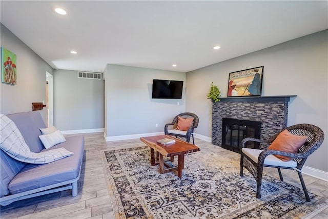 living area featuring light wood finished floors, visible vents, baseboards, recessed lighting, and a fireplace