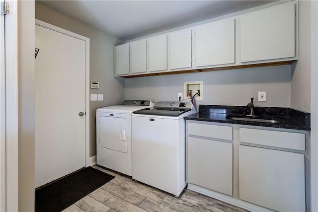 washroom with a sink, cabinet space, and washer and clothes dryer