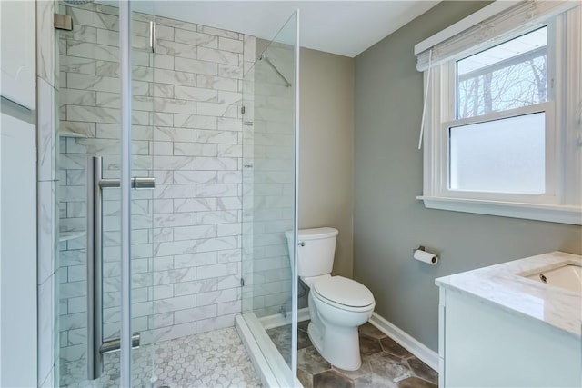 bathroom with vanity, toilet, baseboards, and a stall shower