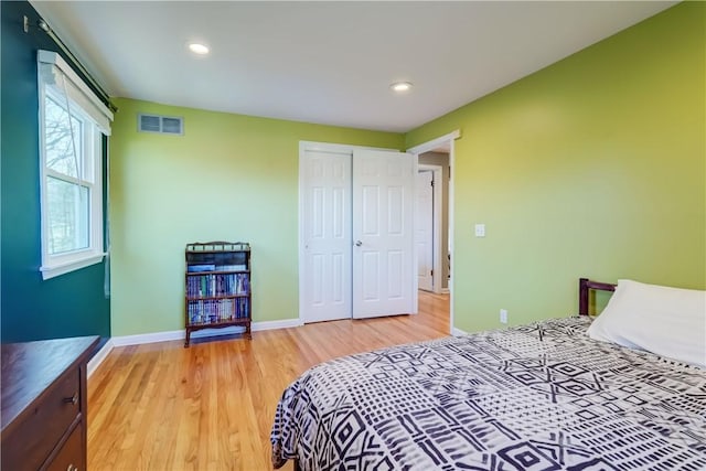 bedroom featuring light wood finished floors, visible vents, baseboards, recessed lighting, and a closet