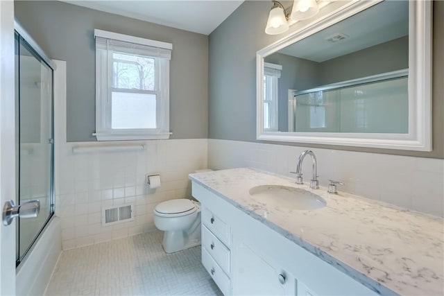 bathroom featuring visible vents, toilet, vanity, tile patterned floors, and tile walls