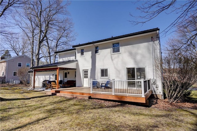 rear view of house with a lawn, a wooden deck, and a garage