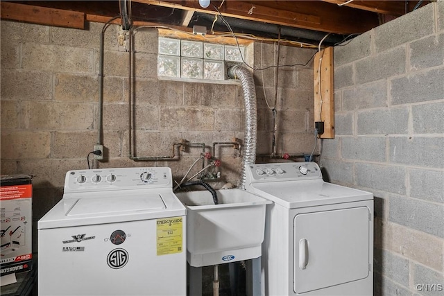 clothes washing area featuring a sink, water heater, laundry area, and washer and clothes dryer