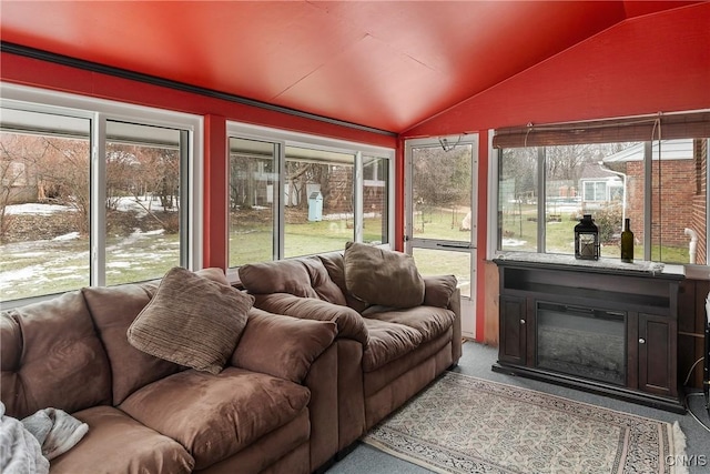 sunroom featuring a glass covered fireplace and lofted ceiling