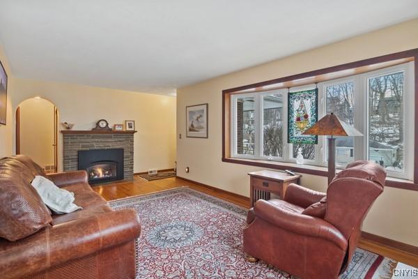 living area with a wealth of natural light, baseboards, a fireplace with flush hearth, and wood finished floors