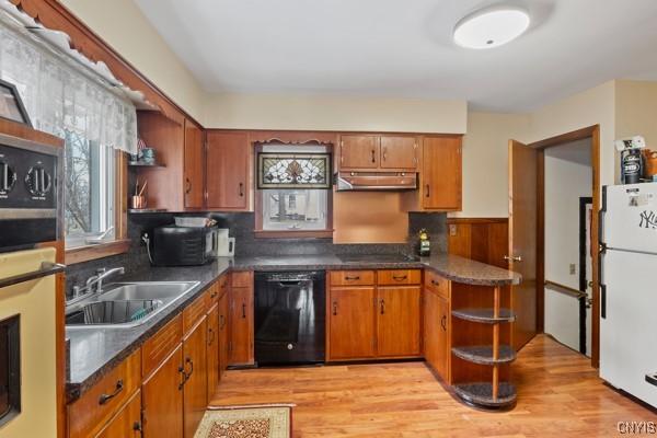 kitchen with open shelves, under cabinet range hood, black dishwasher, freestanding refrigerator, and a sink