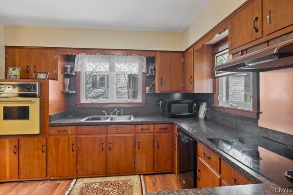 kitchen with brown cabinetry, black appliances, and a sink