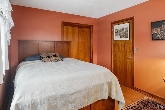 bedroom with a closet, baseboards, and light wood finished floors