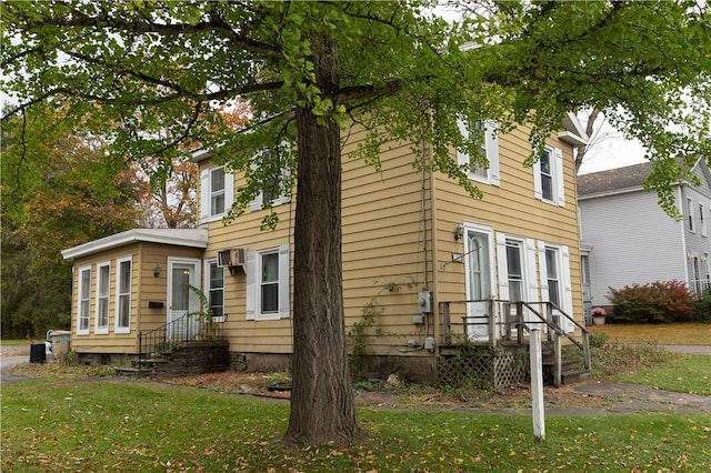 view of front of house with a front yard and a wall unit AC