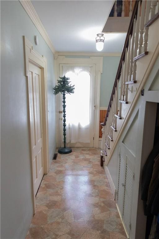 entryway with crown molding, stairway, and stone finish floor