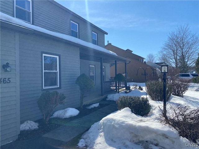 view of snowy exterior with covered porch