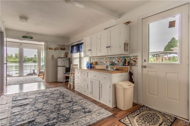 kitchen featuring a sink, light wood-type flooring, white cabinets, and freestanding refrigerator