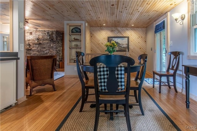 dining room with recessed lighting, light wood-style floors, wooden ceiling, wood walls, and an accent wall