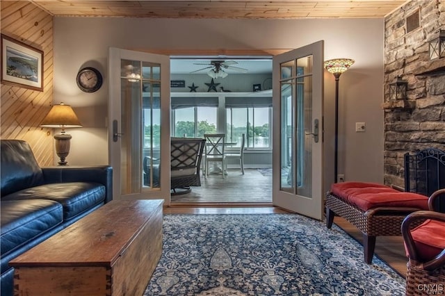 doorway to outside with wood finished floors, a ceiling fan, a fireplace, wood ceiling, and french doors