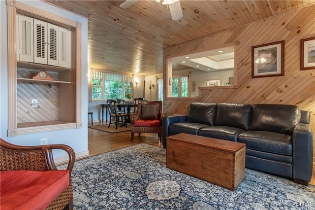 living room featuring a ceiling fan, wooden ceiling, wood finished floors, and wood walls