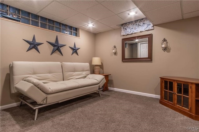 carpeted living area with a paneled ceiling and baseboards