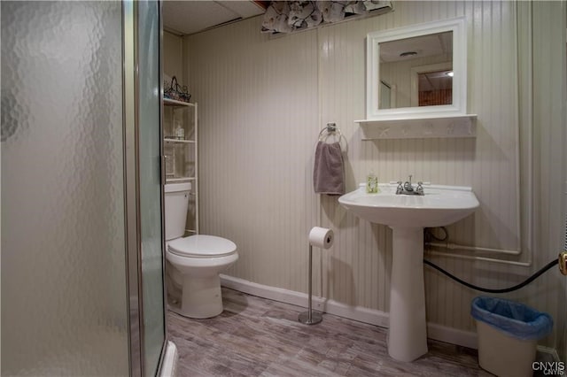 full bathroom featuring toilet, a sink, wood finished floors, a shower stall, and baseboards