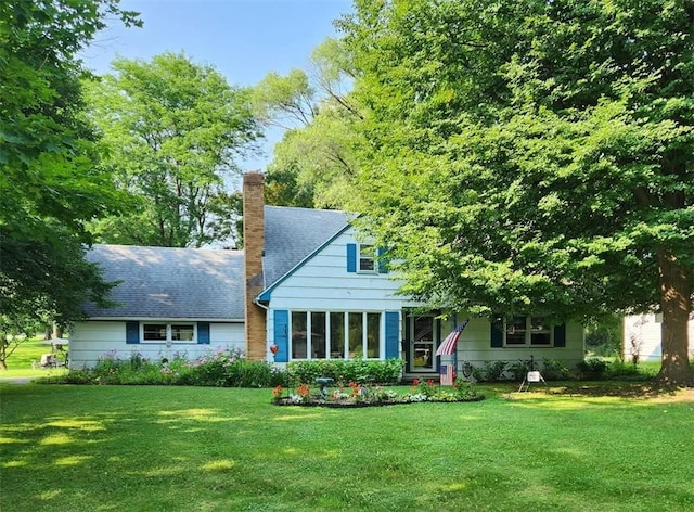 view of front of home with a chimney, a front lawn, and a shingled roof