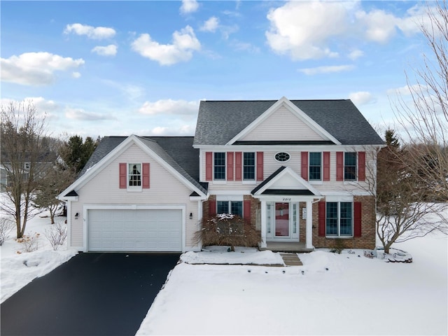 traditional home with aphalt driveway, brick siding, and a shingled roof