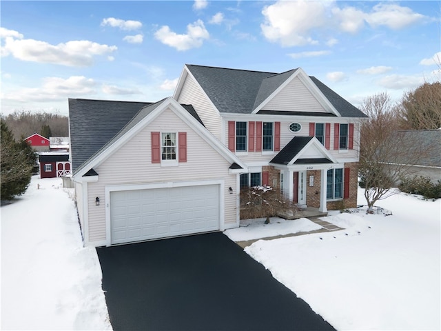 traditional home featuring aphalt driveway, an attached garage, and roof with shingles