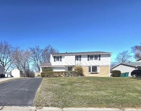 traditional-style home featuring aphalt driveway and a front yard