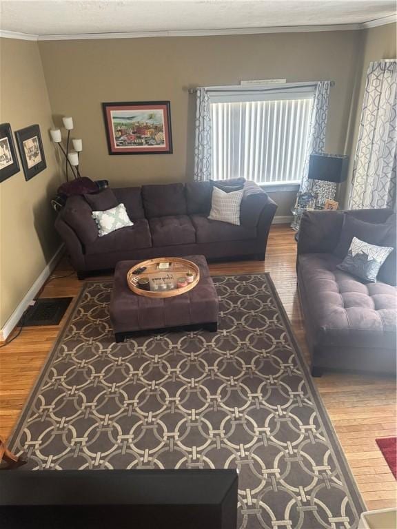 living room featuring visible vents, crown molding, baseboards, and wood finished floors