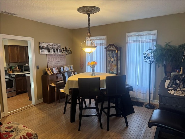 dining space featuring visible vents, light wood-type flooring, and baseboards