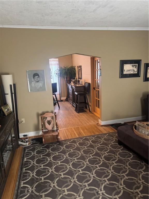 living room featuring a textured ceiling, crown molding, and wood finished floors