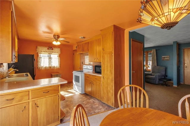 kitchen with freestanding refrigerator, white electric stove, light countertops, and a sink