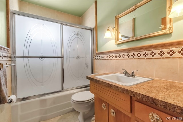 bathroom with vanity, tile walls, toilet, combined bath / shower with glass door, and tile patterned floors