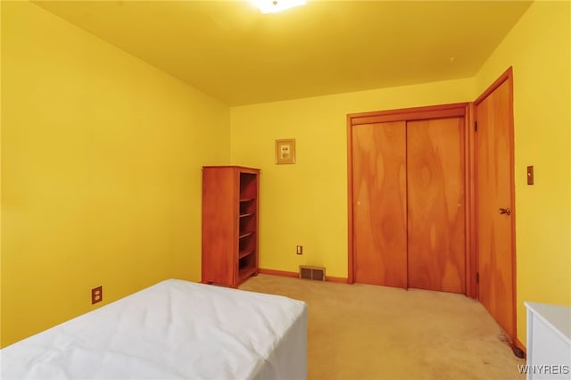 bedroom with a closet, visible vents, and light carpet