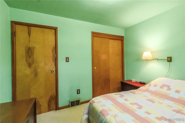 bedroom featuring light colored carpet, visible vents, a closet, and baseboards